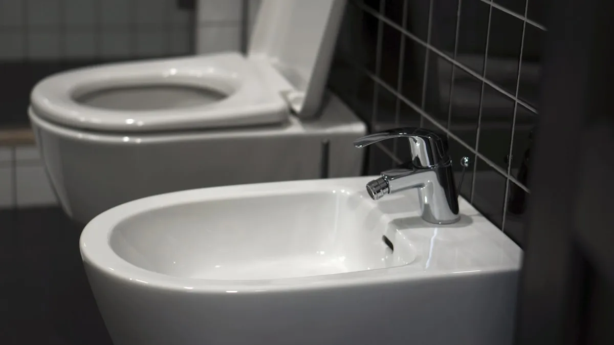A wall-mounted ceramic bidet beside a toilet in a tiled bathroom