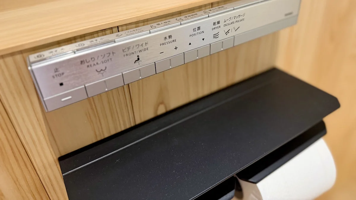 Close-up of a modern bidet seat control panel with wash, pressure, and dryer buttons