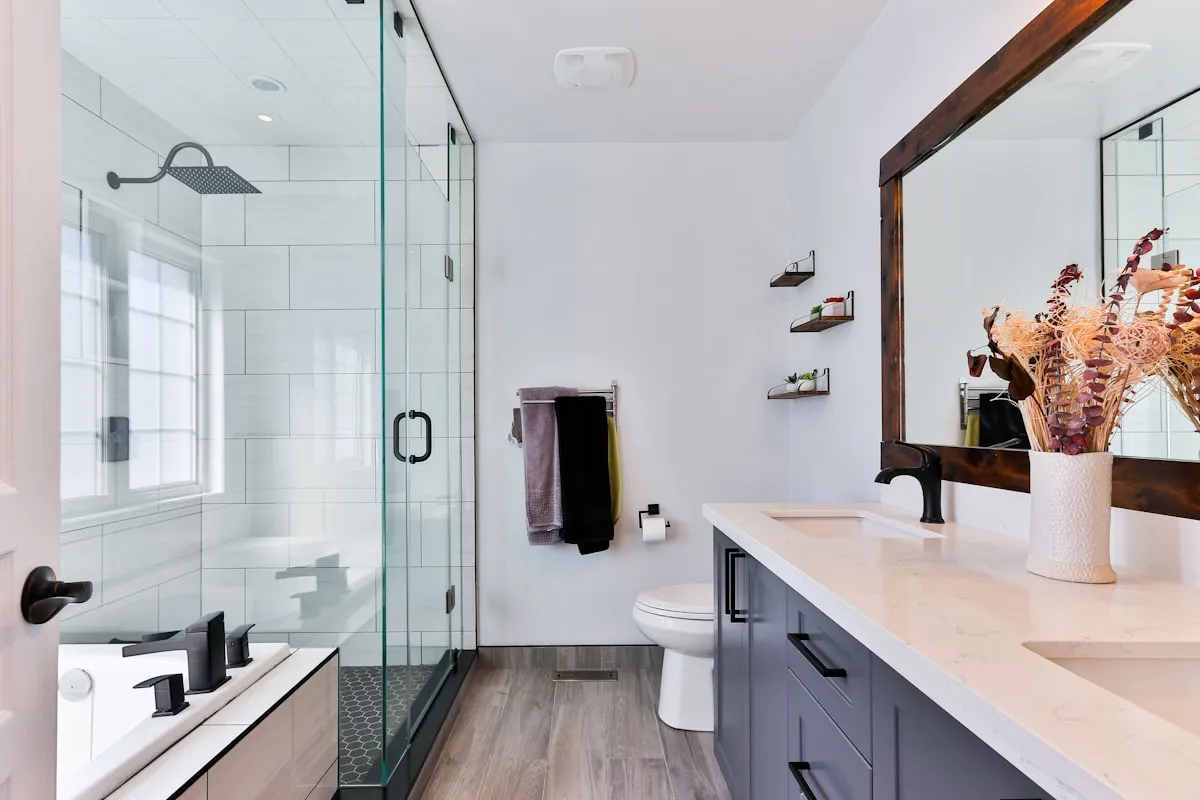 A clean modern bathroom countertop with a calculator, toilet paper rolls, and coins representing bidet cost comparison